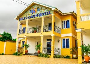 un edificio amarillo con un cartel. en HILLS HAVEN HOTEL, en Accra