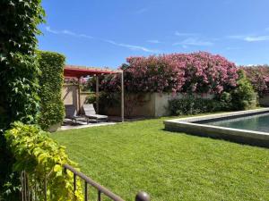 een tuin met een zwembad en roze bloemen bij Mas Ventoux et Vignes 6 adultes + 3 enfants in Mazan
