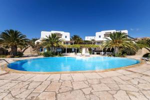 a swimming pool with palm trees and buildings in the background at Verdemare Complex in Mýkonos City