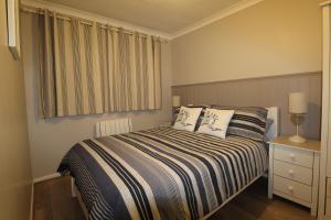 a bedroom with a bed with two pillows and a window at Driftwood Heart in Freshwater