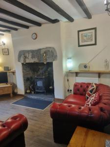a living room with a red couch and a fireplace at Llugwy Cottage in Betws-y-coed