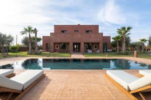 a house with a swimming pool in front of a building at Villa Dar Pampa Marrakech in Marrakesh