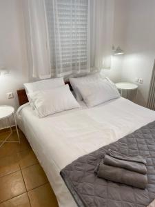 een groot wit bed met 2 kussens en 2 tafels bij Nr1 White appartment w Luxury BA between Train St. and DT in Larisa