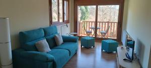 a living room with a blue couch and a balcony at La CASUCA ENTRE TINAS in Pesués