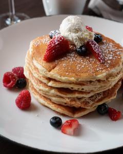 a stack of pancakes with berries and ice cream on a plate at Grand Bohemian Lodge Greenville, Autograph Collection in Greenville