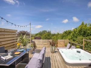 un patio con bañera de hidromasaje en una terraza de madera en 2 Bed in Bude 5.6mls N 86909, en Kilkhampton