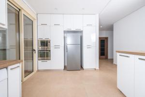 een keuken met witte kasten en een koelkast bij Radieux Appartement à Hydra in Hydra