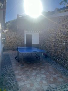a ping pong table in front of a stone wall at Casa rural Cortijo El Verdial in Torrox
