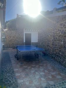 stół do ping ponga przed kamienną ścianą w obiekcie Casa rural Cortijo El Verdial w mieście Torrox
