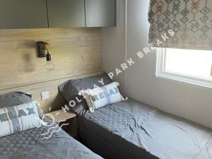 1 dormitorio con 2 camas y ventana en Sunset - A Relaxing Gold 3 bed holiday home at Seal Bay Resort, en Chichester