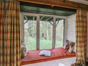 a window with a book sitting on a window sill at Trawsnant Cottage in New Quay