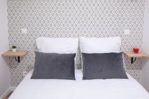 białe łóżko z dwoma poduszkami i dwoma stołami w obiekcie Appartement lumineux proche Parc de la Villette w Paryżu