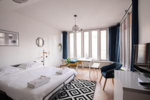 Biała sypialnia z łóżkiem, biurkiem i stołem w obiekcie Appartement lumineux proche Parc de la Villette w Paryżu