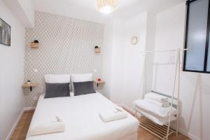 a white bedroom with a bed and a chair at Appartement lumineux proche Parc de la Villette in Paris