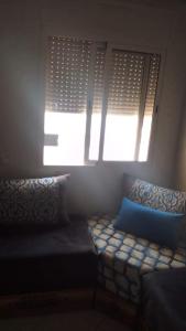 Zimmer mit 2 Fenstern und einem Sofa mit blauen Kissen in der Unterkunft Dar El Ghali in Er Rachidia