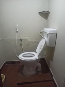 a bathroom with a white toilet with a hose at Uthamar Illam in Tiruchchirāppalli