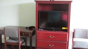 a red entertainment center with a tv and a desk at Sportsman's Motel in Eagle Lake