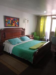 a bedroom with a large bed with a green comforter at HOTEL GALICIA PLAZA in Manizales