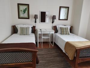 two beds in a room with a table and a desk at Casa das Palmeiras in São Vicente Ferreira
