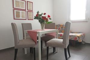 einen Esstisch mit Stühlen und eine Vase mit Blumen in der Unterkunft Bienvenue à Bari! in Bari