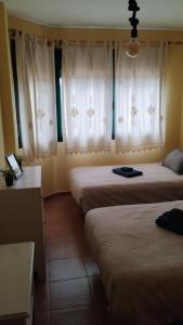 two beds in a room with white curtains at karluchi a Mariña 2 Barreiros in Barreiros +13 photos