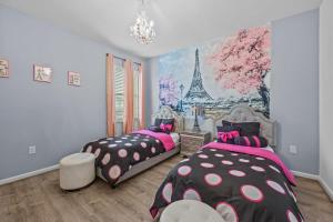2 Betten in einem Zimmer mit einem Wandbild des Eiffelturms in der Unterkunft Luxury Mega Mansion Family Resort Home. 2613 in Kissimmee
