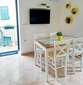 comedor con mesa, sillas y TV en Apartment Megi in Supetar historical core, en Supetar