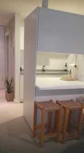 une cuisine avec deux tabourets et un comptoir blanc dans l'établissement Departamento hermoso en Almagro, à Buenos Aires
