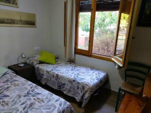a room with two beds and a window and a chair at Cosy Chalet in L'Arboçar with Private Pool, 65 sqm in Barcelona