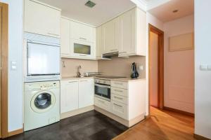 a kitchen with white cabinets and a washer and dryer at One bedroom appartement with wifi at Baiona in Baiona