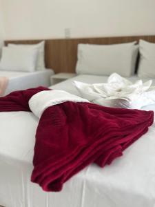 um cobertor vermelho e branco em cima de uma cama em Hotel Areião em Goiânia
