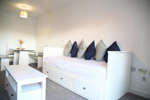 Dormitorio blanco con cama blanca y almohadas azules en Windsor to Heathrow spacious 2 Bedroom 2 Bath Apartment with Parking - Langley village Elizabeth Line to London, Reading, Oxford en Slough