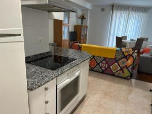 a kitchen with a stove top oven next to a living room at Piso Alameda Carballiño in Carballino