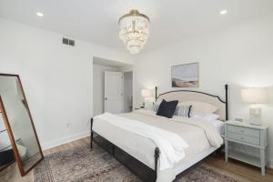Habitación blanca con cama grande y lámpara de araña. en Silverwood Serenity: Large 2b 2b with Parking en Filadelfia