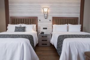 Habitación de hotel con 2 camas con sábanas blancas en Hotel Ronda Minerva, en Guadalajara