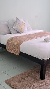 un letto con coperta e cuscini sopra di Tamiasuites Apartment a Kisumu