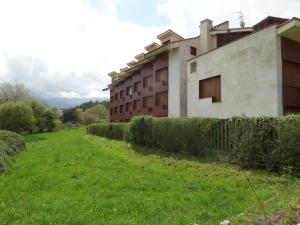a building in a field next to a fence at Apartamento con jardín in Barro de Llanes