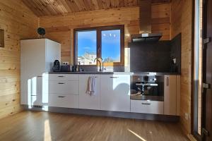 a kitchen with white appliances in a room with wooden walls at Chalet Hermillon des Ardennes in Fromelennes