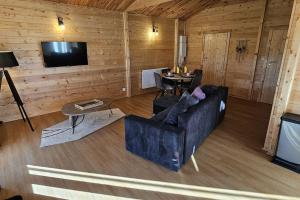 a living room with a couch and a table at Chalet Hermillon des Ardennes in Fromelennes
