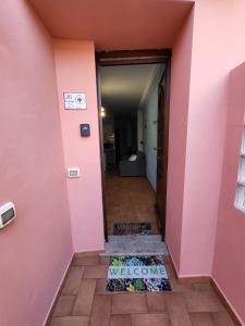 um corredor com uma parede cor-de-rosa e um tapete de boas-vindas em La brezza marina em SantʼAntìoco