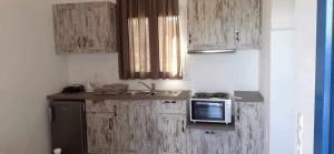 a small kitchen with wooden cabinets and a microwave at SOHOROS STUDIOS in Irakleia