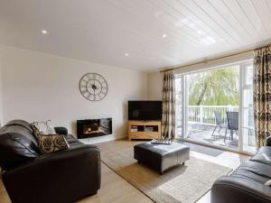 uma sala de estar com mobiliário de couro preto e uma grande janela em 3 Bed in Cirencester HIC02 em South Cerney