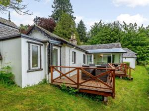 a house with a wooden deck in the yard at 5 Bed in Loch Ness 78538 in Drumnadrochit