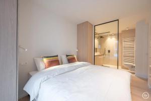 Un dormitorio con una gran cama blanca y un baño. en Verliefd aan zee, en Knokke-Heist