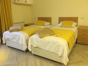 two beds in a room with yellow sheets at Guesthouse in Historic Village in Aghtsʼkʼ