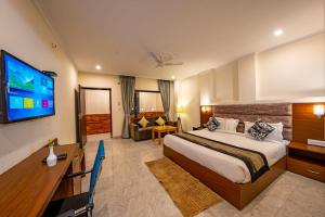 a hotel room with a bed and a flat screen tv at The Himalayan Stays Nainital in Nainital