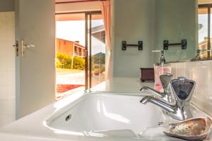 a white bathroom sink with a mirror and a window at Edible Shores in Pringle Bay +52 photos