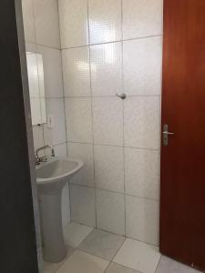 a white bathroom with a sink and a shower at Pousada Sitio Urbano in São José da Barra