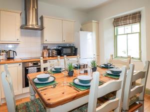 una cocina con una mesa de madera con sillas alrededor. en Glen Cottage - Torridon, en Achnasheen