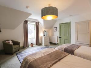 a bedroom with two beds and a chair and a window at Glen Cottage - Torridon in Achnasheen